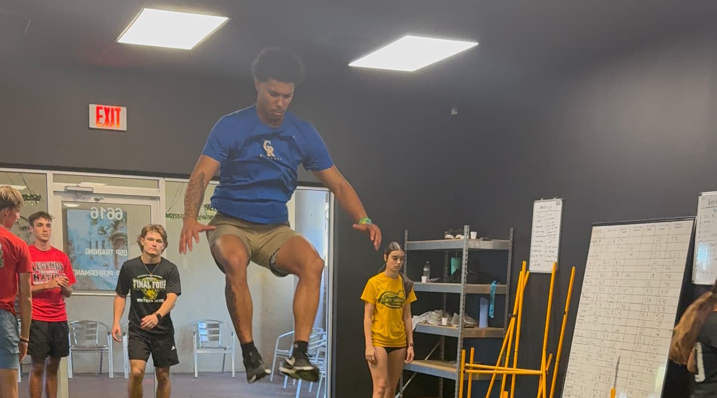 Athlete mid-jump while teammates watch at Dynamic Sports Performance in Crystal River