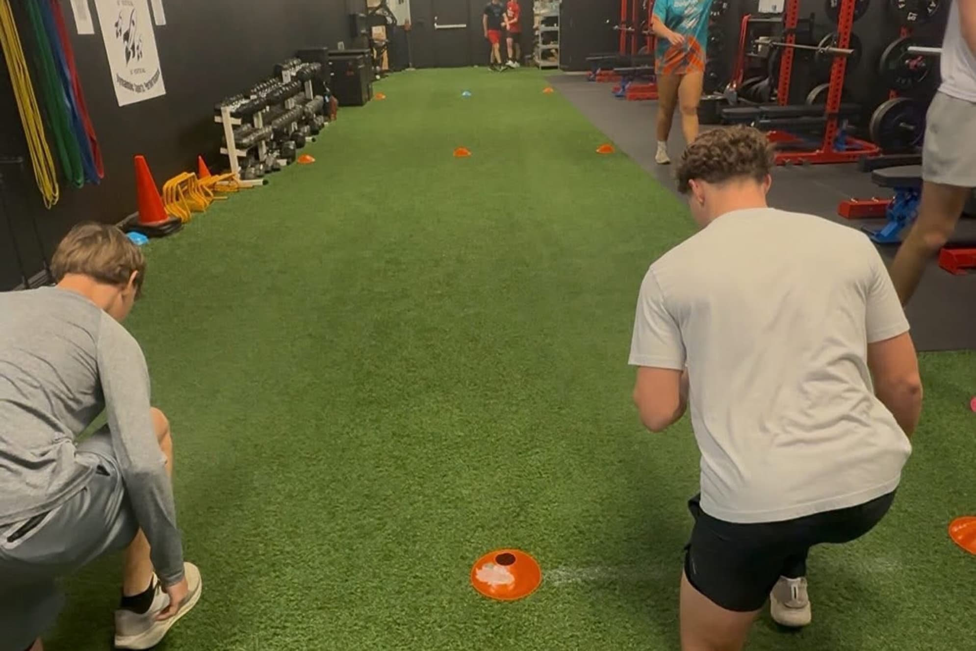 Two athletes set at the cones for a lateral shuffle start on the turf