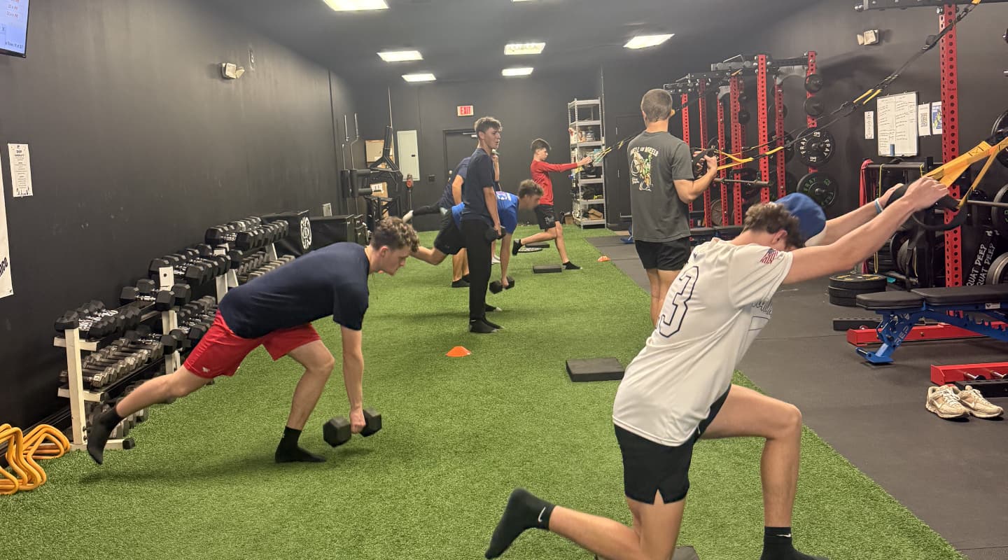 Group of athletes doing dumbbell lunges and band pulldowns