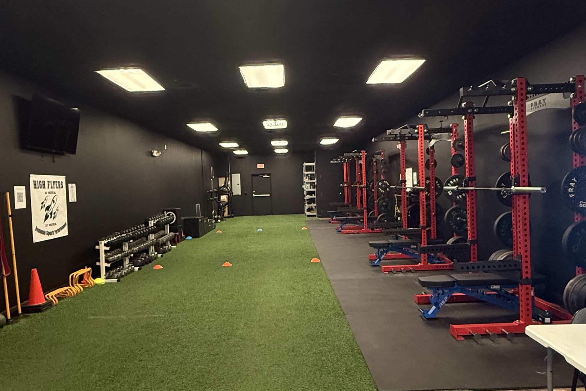 Inside the Dynamic Sports Performance facility: turf lane, squat racks and dumbbells